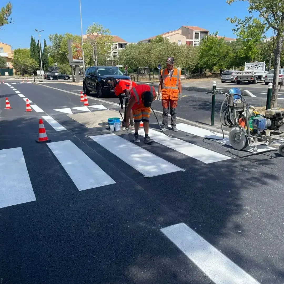 Équipe ASM traçant un passage piéton sur une avenue, machine de traçage et cônes en protection