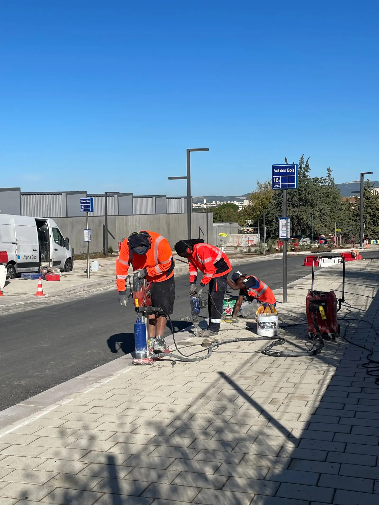 Équipe ASM posant du mobilier le long d’une voirie, fourgon à proximité
